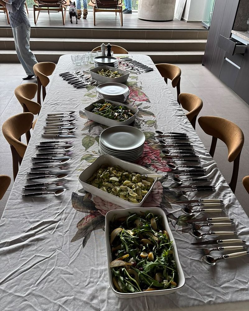 Mesa larga montada con ensaladas, platos y cubiertos